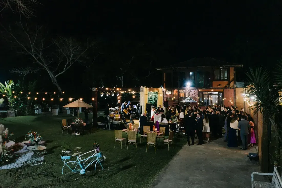 Festa de casamento à noite, com varais de luz acesos sobre o gramado