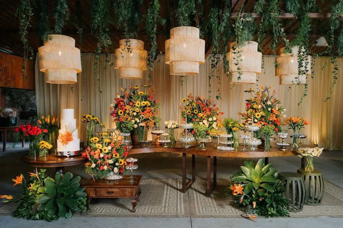 Mesa do bolo decorada com flores e luminárias de fibra natural